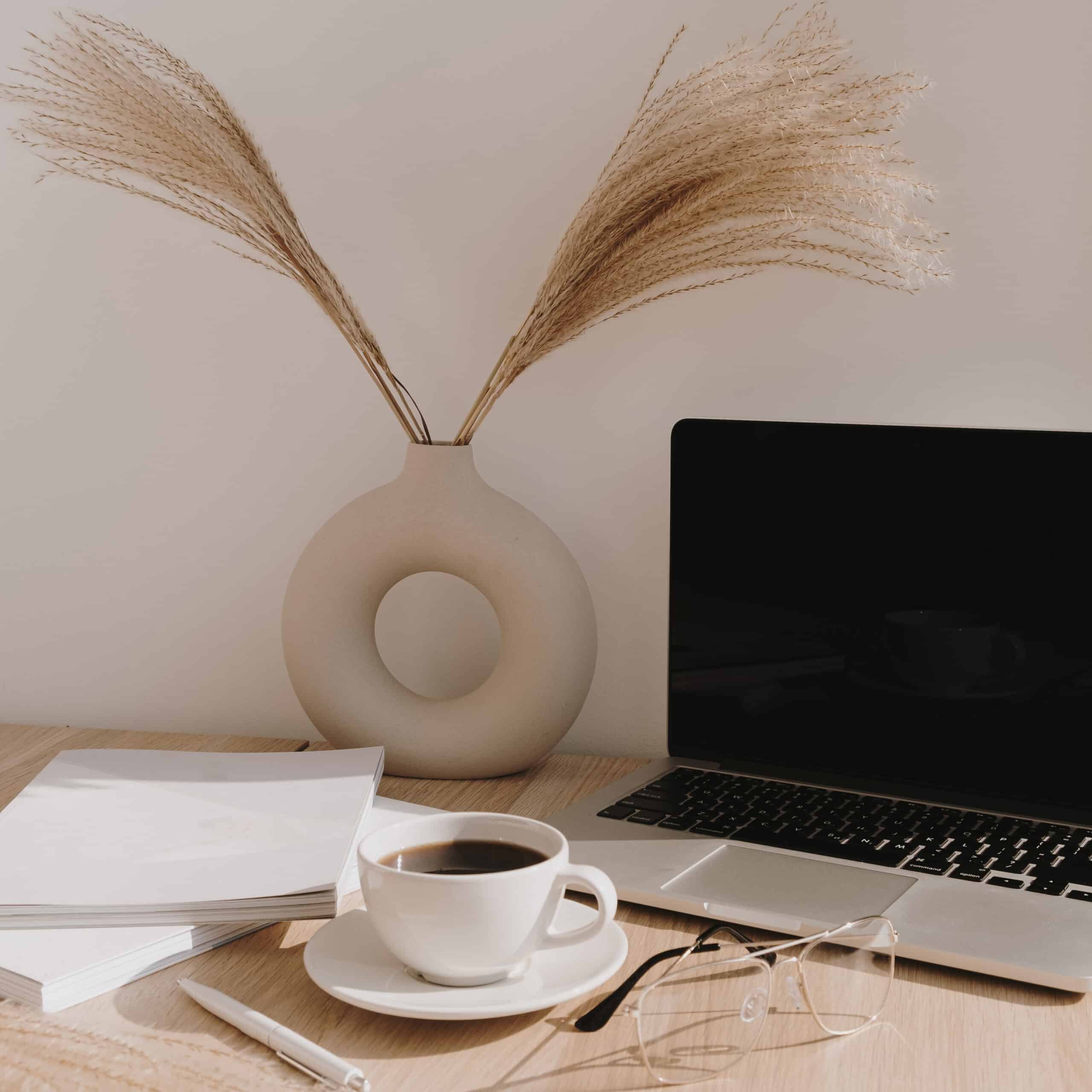 female-home-office-desk-workspace-blank-screen-laptop-computer-with-copy-space-coffee-cup-pampas-grass-stylish-vase-beige-wooden-table